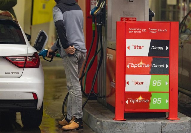 Una persona echa gasolina del surtidor de una gasolinera.