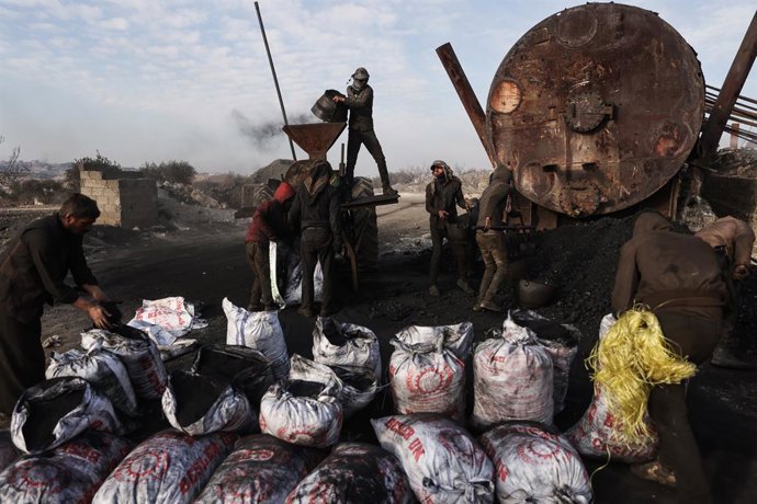 05 December 2022, Syria, Al Bab: Syrian workers extract coal at a primitive oil refinery in the village of Tarhin, where fuels are extracted from crude oil coming from the wells controlled by the Syrian Democratic Forces. Despite the high risk, many you