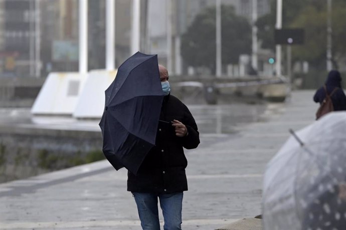 Archivo - Un hombre con un paraguas camina por el paseo marítimo mientras llueve en el paseo marítimo de A Coruña