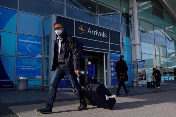 Archivo - Un hombre con mascarilla camina en el exterior del aeropuerto de Birmingham