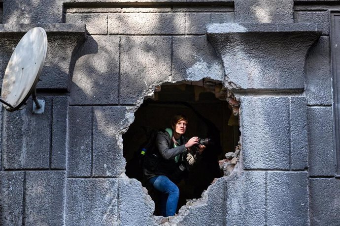 Archivo - 21 October 2022, Ukraine, Zaporizhzhia: A journalist peeps out from the hole in the wall of a residential building damaged as a result of a rocket attack by the russian troops. Photo: -/Ukrinform/dpa