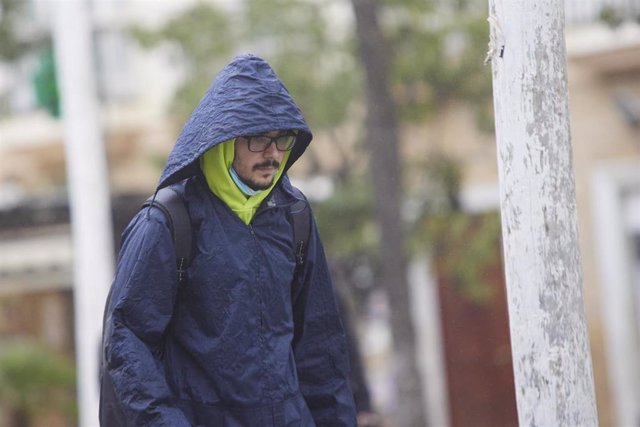 Un chico se aguarda de la lluvia con un chubasquero durante la llegada de la borrasca Efraín a Cádiz, a 13 de diciembre de 2022 en Cádiz (Andalucía, España). 