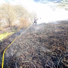 Archivo - Bomberos extiguen en Los Corrales de Buelna un incendio forestal ya apagado que se había reavivado.- Archivo