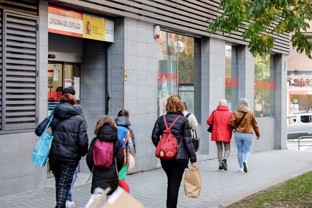 Archivo - Varias personas pasan frente a una oficina de empleo en Madrid