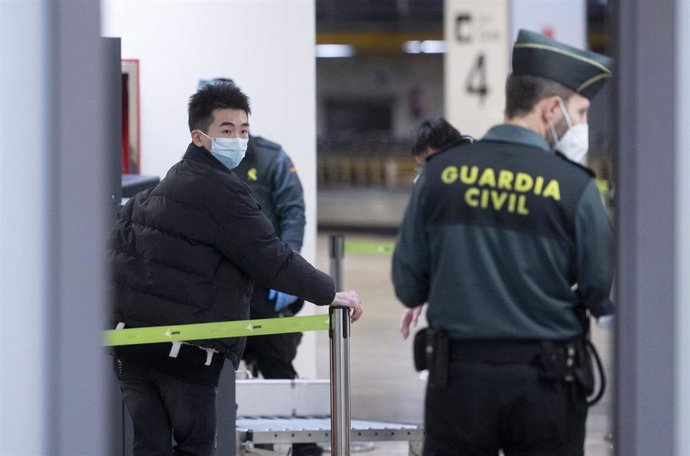 Un agente de Guradia Civil con un pasajero que llega al aeropuerto Adolfo Suárez Madrid-Barajas procedente de un vuelo de Chongqing (China), a 3 de enero de 2023, en Madrid (España).  