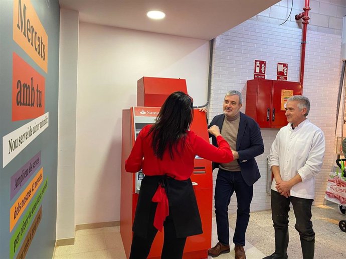 El primer teniente de alcalde de Barcelona, Jaume Collboni, visita el cajero automático en el Mercat del Bess junto a paradistas.