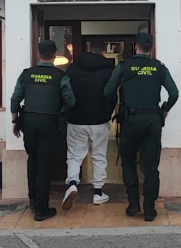 Dos guardias civiles sujetan el detenido.