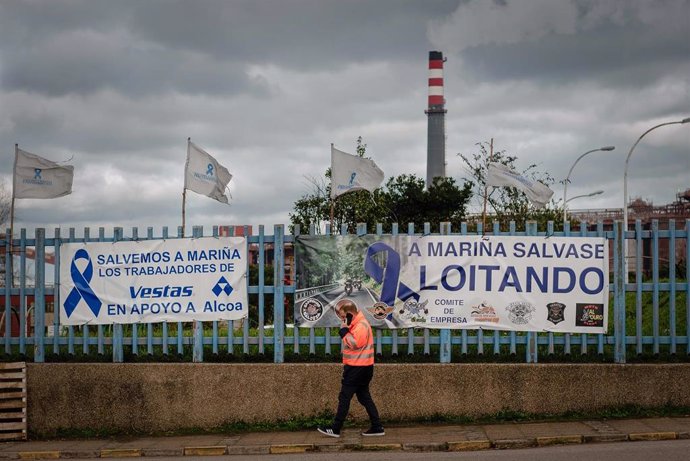 Archivo - Una persona pasa delante de una pancarta, colocada por los trabajadores en la valla de la fábrica de Alcoa en San Cibrao, un día después de que los trabajadores alcanzaran un acuerdo con la empresa, a 29 de diciembre de 2021, en San Cibrao, Ce