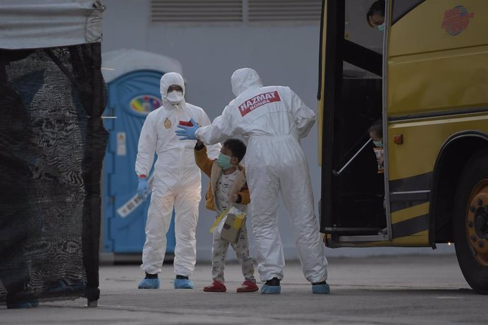 Archivo - Trabajadores con trajes de protección ayudan a un niño en un minubús en Malasia