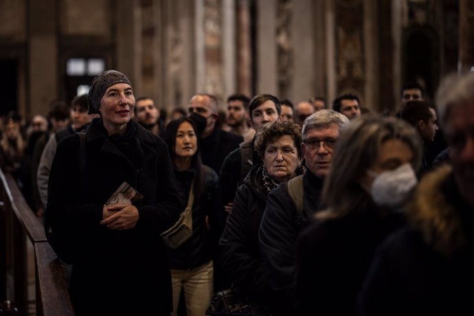 04 January 2023, Vatican, Vatican City: A mourner holds a picture of late Pope Emeritus Benedict XVI as she queues in St. Peter's Basilica at the Vatican where the body of late Pope is laid out in state. Photo: Oliver Weiken/dpa