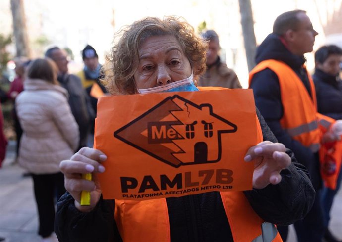 Una mujer porta una pancarta de la Plataforma de Afectados Metro L7B en la plaza de la Fuente del Trébol.