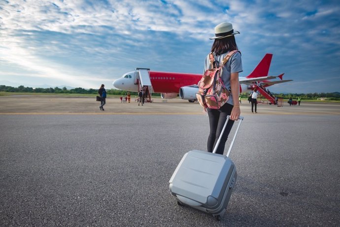 Archivo - Girl traveler with luggage going to plane