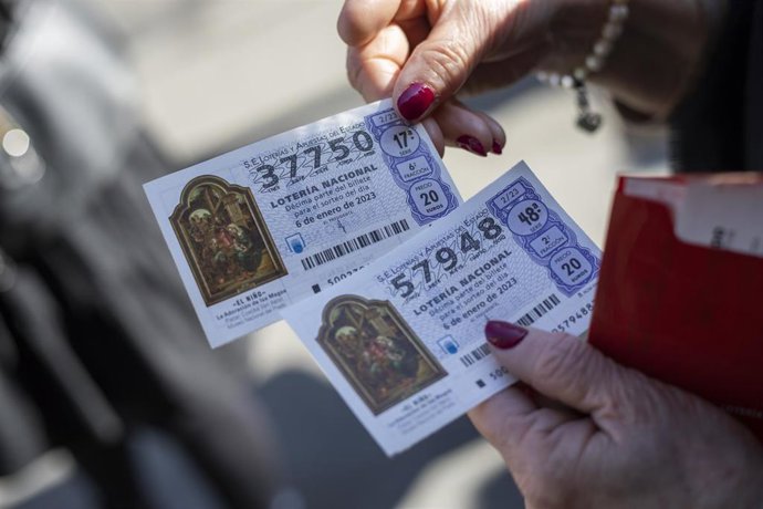 Una mujer sostiene dos décimos para el Sorteo Extraordinario de El Niño