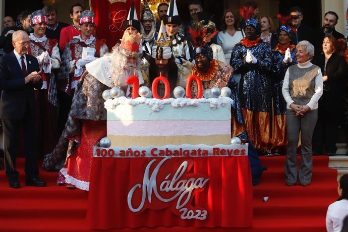 Los Reyes Magos de Oriente soplan las velas de una gran tarta por el centenario de la cabalgata de Málaga capital.