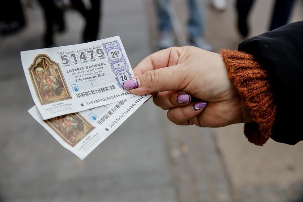 Una mujer sostiene dos décimos para el Sorteo Extraordinario del Niño, a 2 de enero de 2023, en Madrid