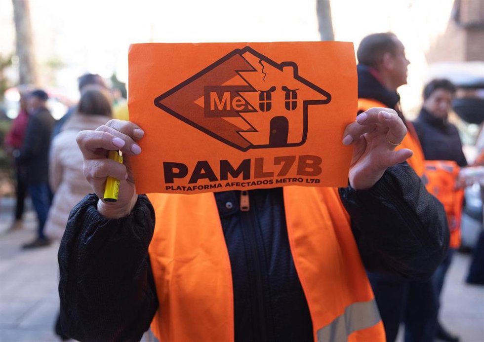 Una mujer porta una pancarta de la Plataforma de Afectados Metro L7B en la plaza de la Fuente del Trébol.