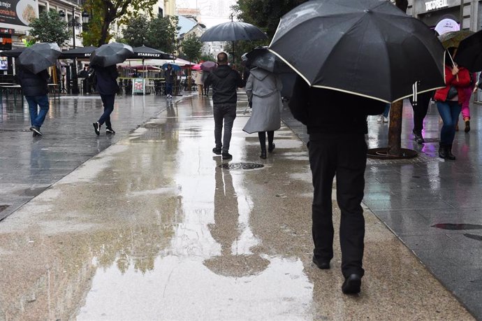 Personas caminan por la calle con paraguas, a 13 de diciembre de 2022, en Madrid (España). 