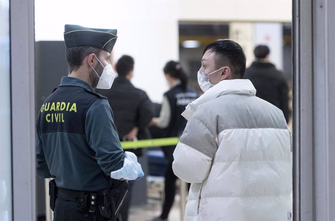 Un agente de Guradia Civil con un pasajero que llega al aeropuerto Adolfo Suárez Madrid-Barajas procedente de un vuelo de Chongqing (China), a 3 de enero de 2023, en Madrid (España).