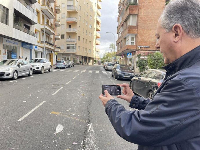 El candidato del PP a la Alcaldía de Sevilla, José Luis Sanz, toma una foto de una calle con caramelos en el suelo.
