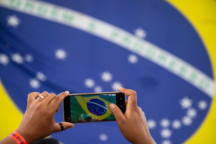 31 December 2022, Brazil, Brasilia: A supporter of Lula da Silva from Brazil takes a picture in a camp at the Mané Garrincha stadium in Brasilia. Photo: Santiago Mazzarovich/dpa