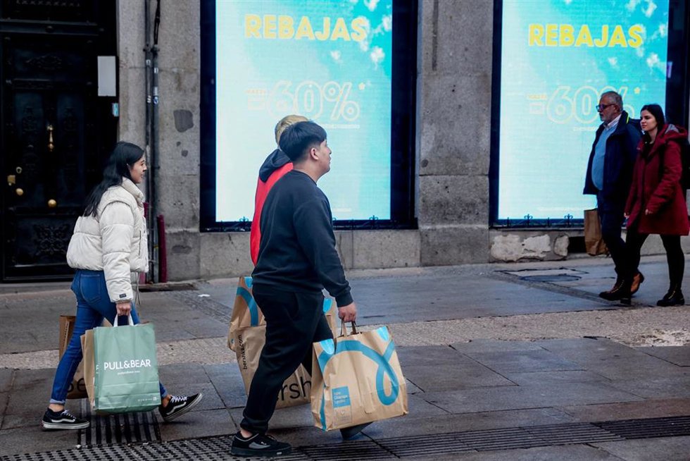 Varias personas caminan por una calle comercial de Madrid tras comprar en las rebajas
