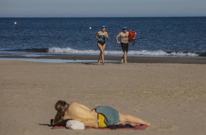Dos personas en bañador caminan por la orilla de la playa, a 24 de diciembre de 2022, en Valencia