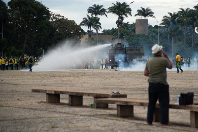 08 January 2023, Brazil, Brasilia: Supporters of former Brazilian President Jair Bolsonaro are pelted with water cannon during clashes with law enforcement officers in the capital. Supporters of former Brazilian President Bolsonaro have stormed the Cong