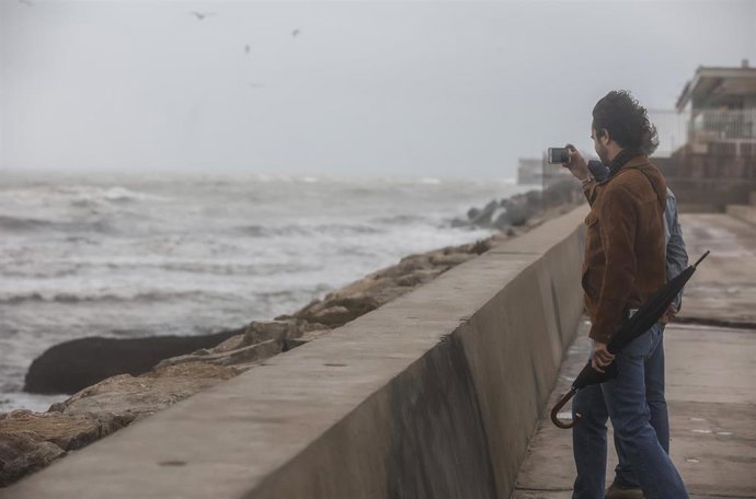 Archivo - Dos personas fotografían el mar, en un día de viento, en una playa de la Comunitat