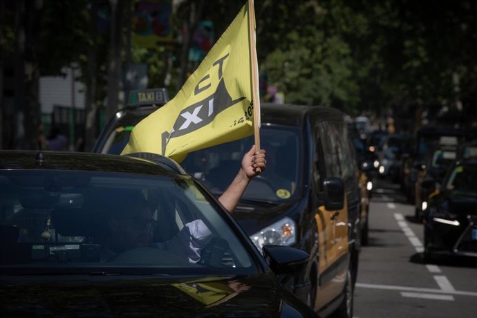 Archivo - Un taxista ondea una bandera en una marcha lenta de taxistas contra los VTC en una imagen de archivo.