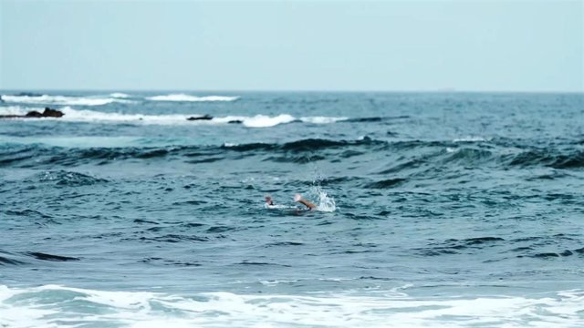 Persona sufriendo para mantenerse a flote en una playa