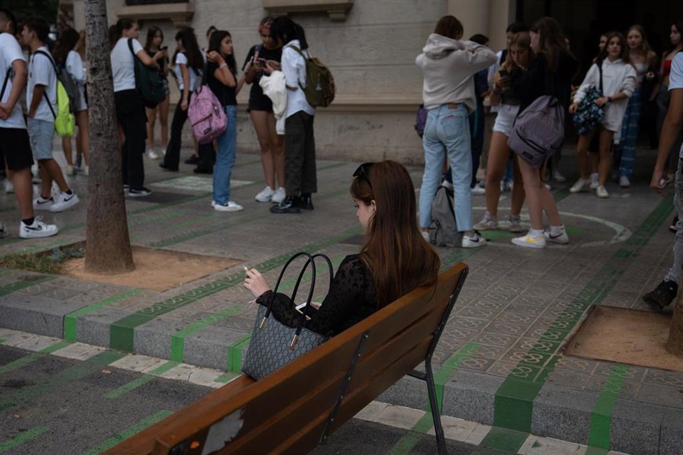 Archivo - Una mujer fuma sentada en un banco a la salida del colegio Pia Balmes