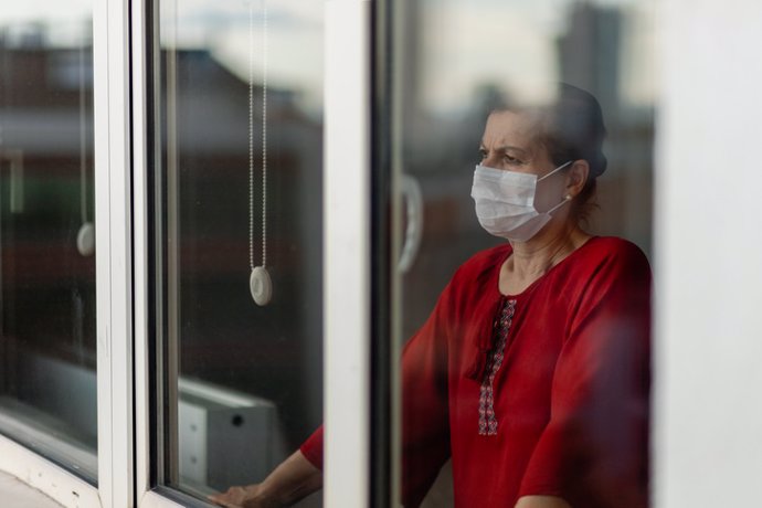 Archivo - Mujer en la ventana de casa. Cuarentena. Mascarilla. Covid-19