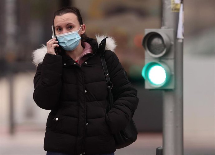 Archivo - Una persona con mascarilla junto a su bicicleta.