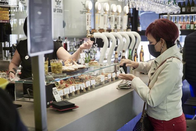 Archivo - Una mujer paga su consumición en el interior de un bar