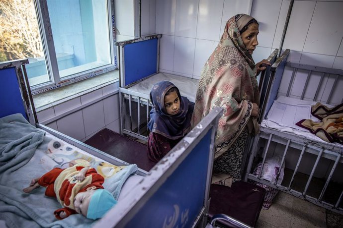 Archivo - 14 November 2022, Afghanistan, Kabul: An Afghan mother and her daughter are seen next to an infant in a ward for severe malnutrition in a hospital in Kabul. According to "Save the Children," the number of dangerously malnourished children in A