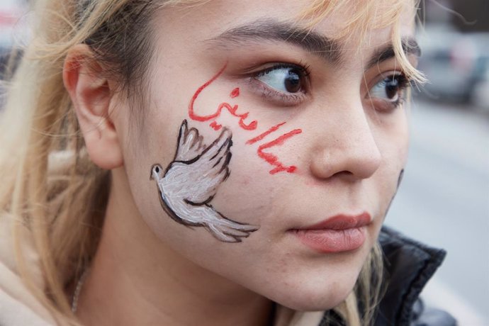 14 January 2023, Hamburg: A peace dove and the Persian name Mahsa Amini, an Iranian woman who died during her imprisonment, is seen painted on the face of a demonstrator during a motorcade in a solidarity with the people of Iran. Photo: Georg Wendt/dpa