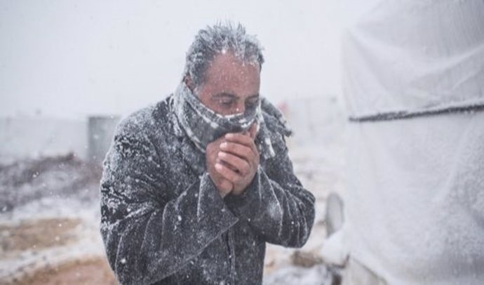 Un hombre se calienta las manos durante una ventisca en Irán