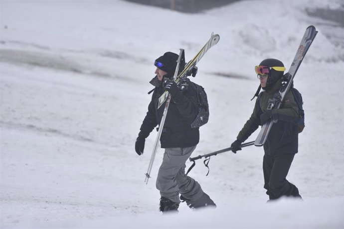 Archivo - Dos personas portan sus esquís.