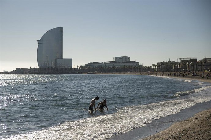 Una pareja se baña en la playa de la Barceloneta, a 25 de diciembre de 2022, en Barcelona, Cataluña (España). La playa de Barcelona ha amanecido hoy, día de Navidad con gente tomando el sol y algunos incluso bañándose, aprovechando el sol y la buena tem