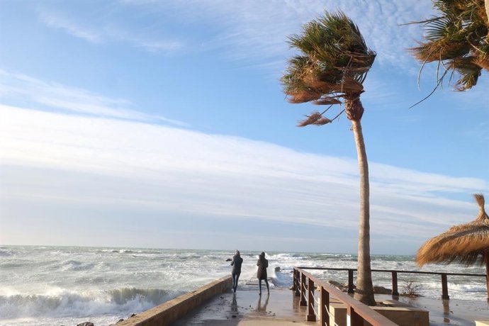 Dos jóvenes ante las olas en Palma por el fuerte viento.