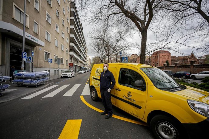 Archivo - Un repartidor de Correos al lado de su vehículo de trabajo 