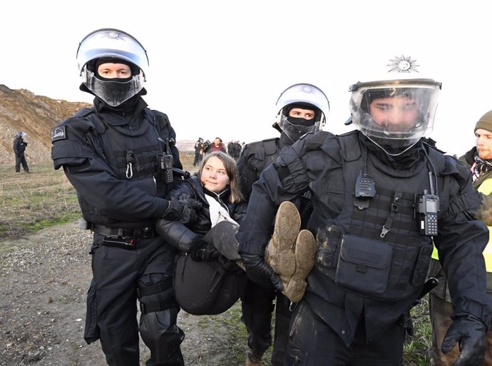 17 January 2023, North Rhine-Westphalia, Erkelenz: Police officers carry Swedish climate activist Greta Thunberg (C) out after taking part in a protest after the evacuation of Luetzerath. Photo: Roberto Pfeil/dpa