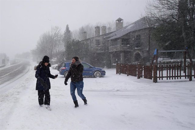 Dos personas caminan por una acera nevada, a 17 de enero de 2023, en Pedrafita do Cebreiro, Lugo, Galicia (España). 