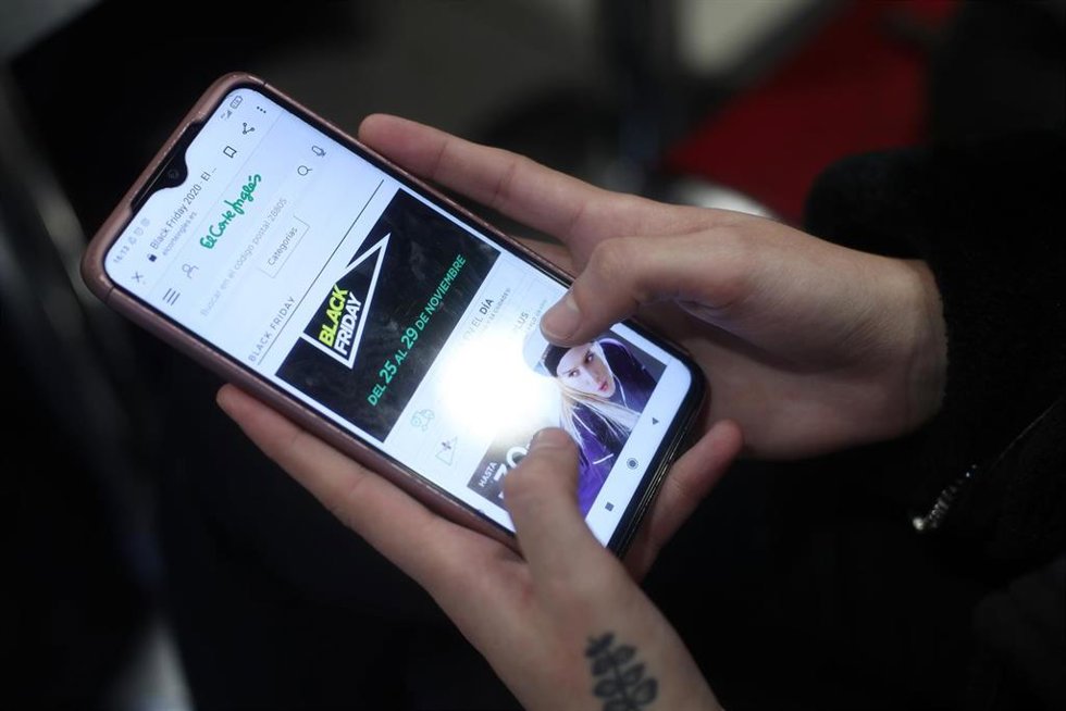Archivo - Una joven consulta las ofertas de Black Friday de un comercio en su móvil, 