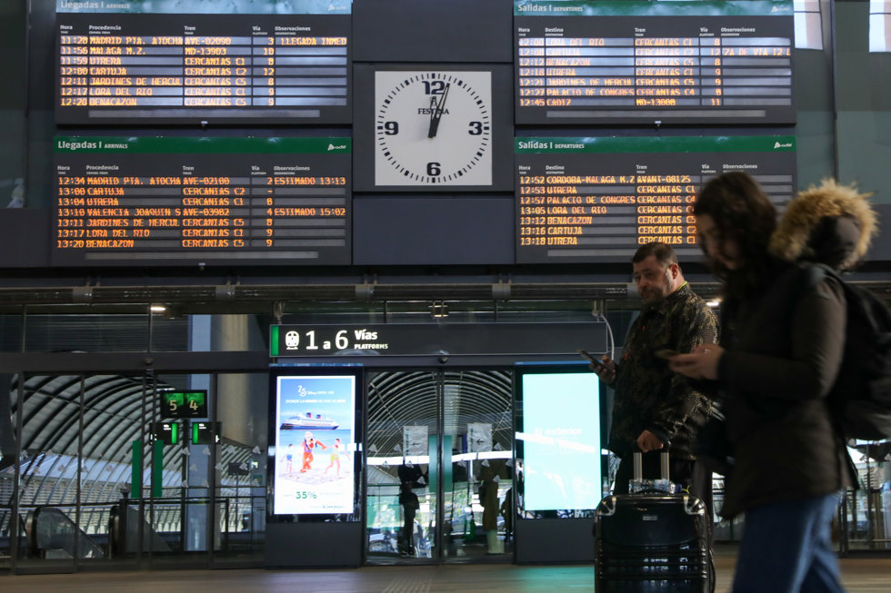 Pasajeros en la estación ferroviaria de Santa Justa, con el panel de horarios de los trenes al fondo.