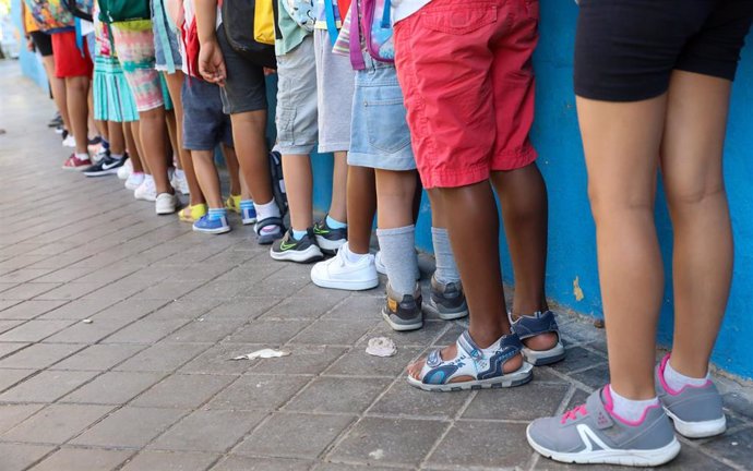 Archivo - Varios niños hacen fila con sus mochilas