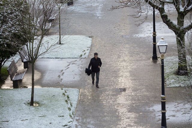 Un hombre pasea sobre una ligera capa de nieve junto a la muralla romana de Lugo, a 18 de enero de 2023, en Lugo, Galicia (España). La cota de nieve está en 400 metros y ha sido acompañada por un descenso de las temperaturas. La situación más complicada e
