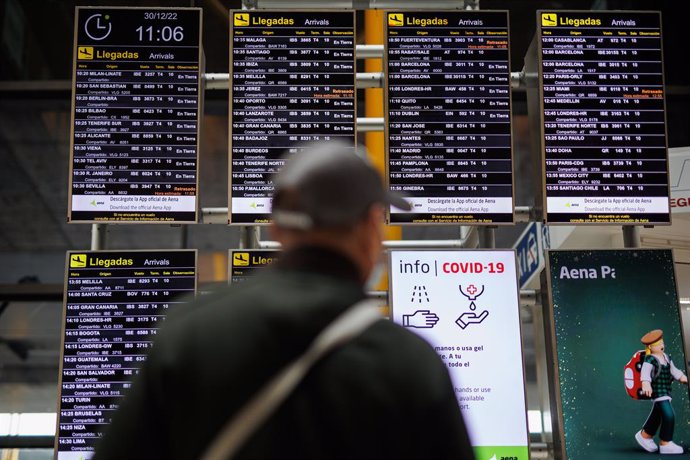 Un hombre con mascarilla observa los paneles informativos de las salidas de los vuelos en el aeropuerto Adolfo Suárez Madrid-Barajas, a 30 de diciembre de 2022, en Madrid (España). 