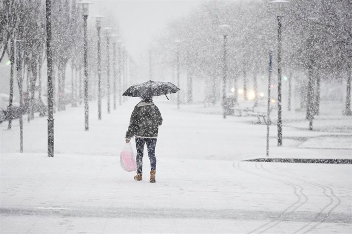 Una mujer camina bajo la nieve, a 18 de enero de 2023, en Pamplona, Navarra (España).