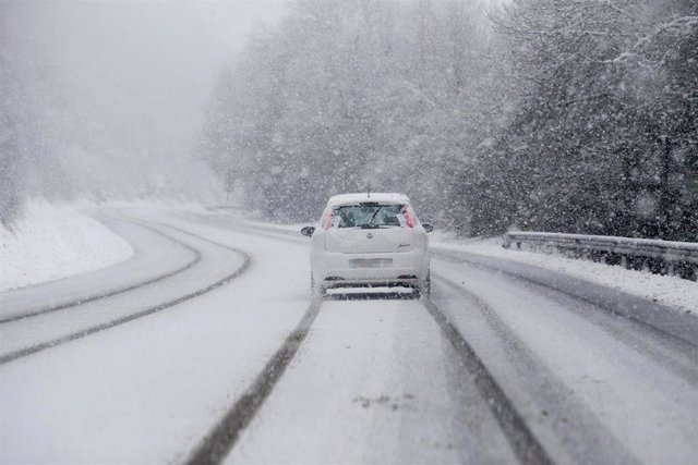 Un coche conduce por una carretera cubierta de nieve, a 18 de enero de 2023, en Castroverde, Lugo, Galicia (España).